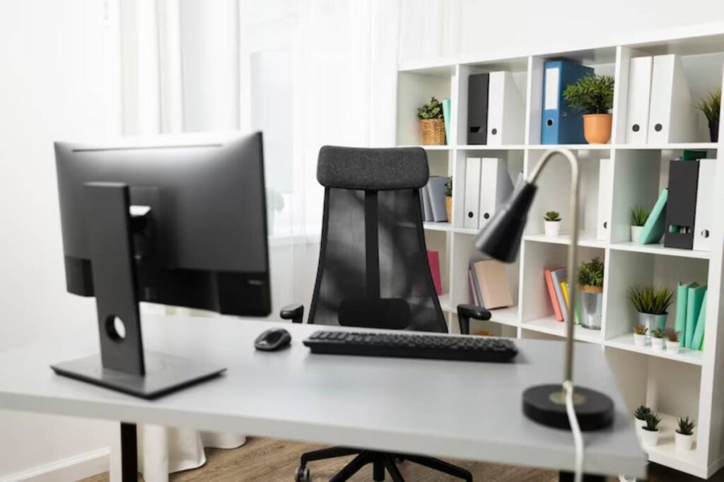 Modern office setup featuring a sleek desk with a computer, ergonomic chair, and organized shelves with books and plants.