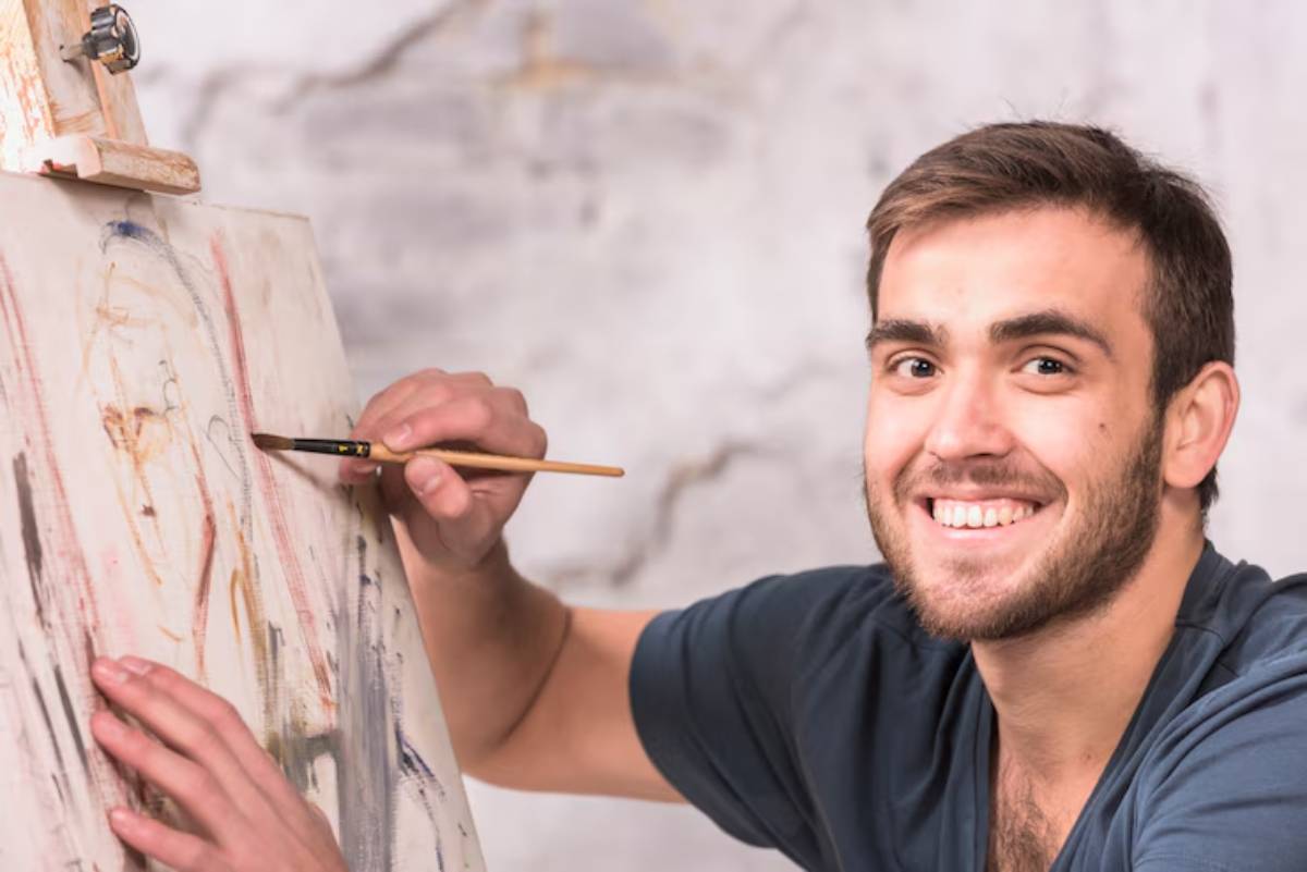A person is painting on a canvas with a brush, showcasing a blend of colors and artistic expression in a bright, serene setting. 